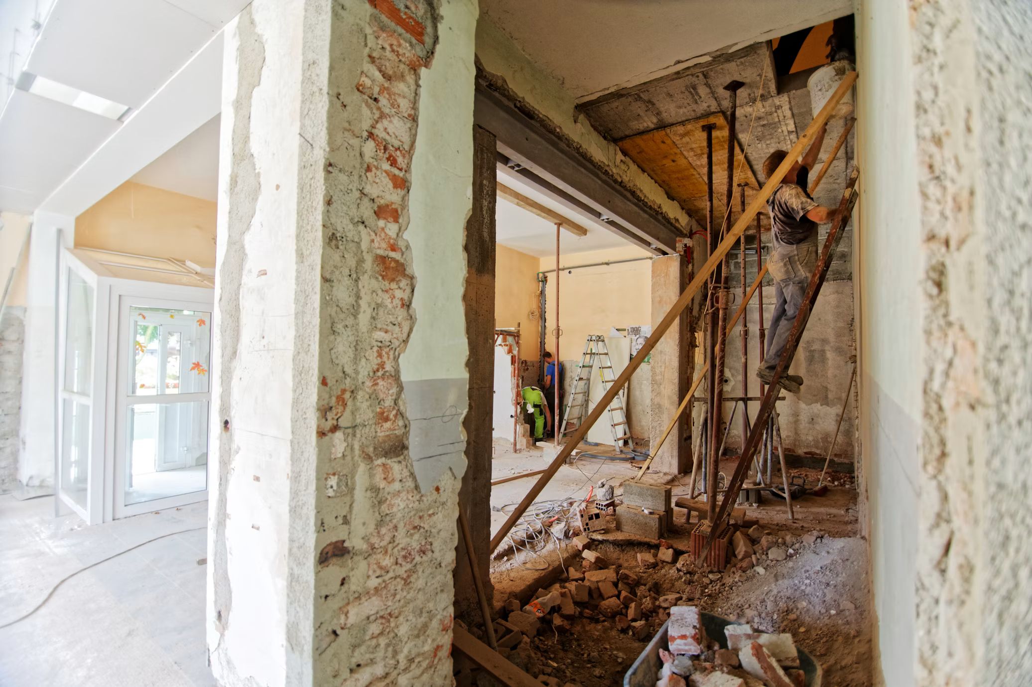 Isometric perspective of a room being renovated. On the left side, fixtures, flooring, and windows appear complete with white paint;
on the right side a room appears laid bare with exposed flooring, walls, and ceiling, as an unrefined work in progress.
